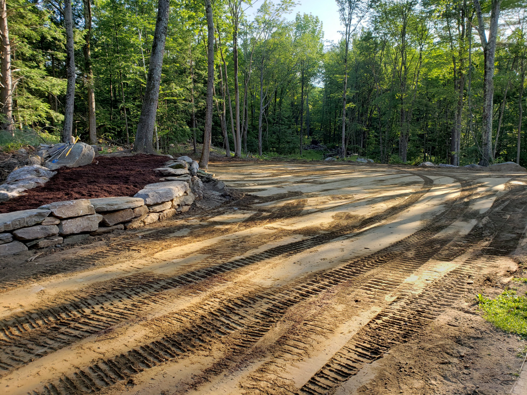 Finish-graded residential site with stabilized slopes and stone retaining wall