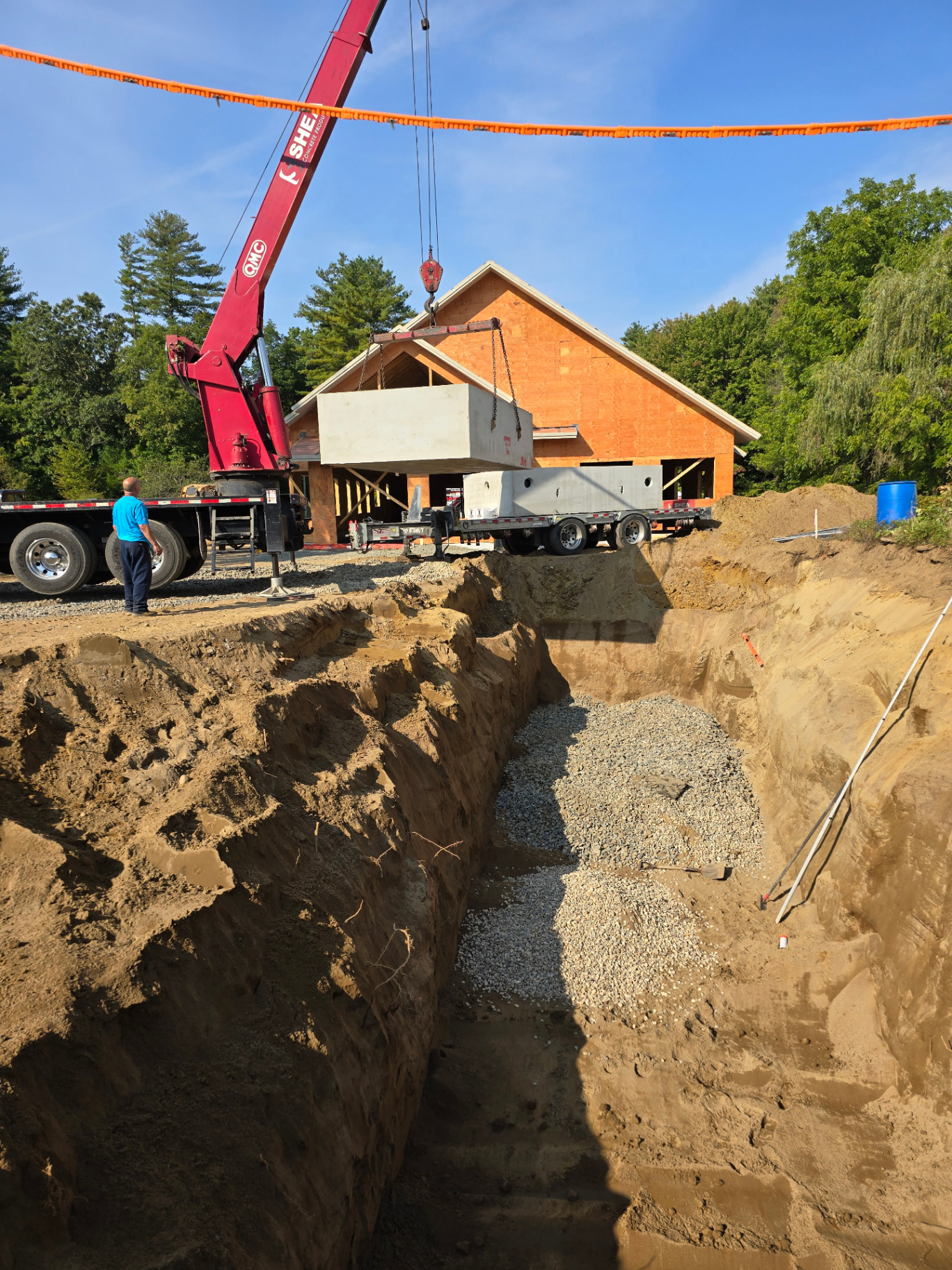 Precast septic tank component being lowered into an excavated installation area during new construction.